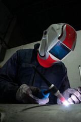 welder operator, welding with electric arc welder and white mask