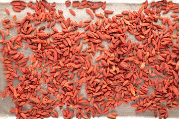 Dried organic goji berries on a metal tray , macro, top view.