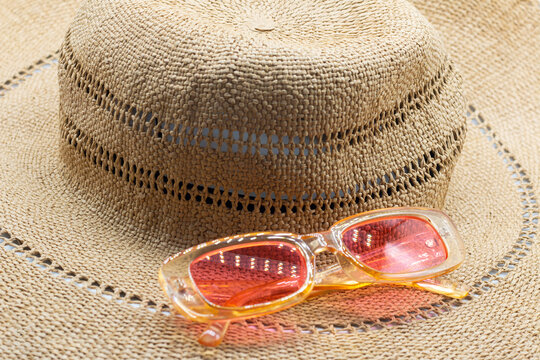 Straw hat and glasses of pink color. The image of summer