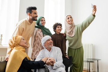 happy arabian woman taking selfie on smartphone with multicultural muslim family.