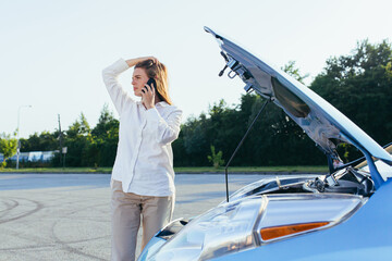 An annoyed and angry woman, near a broken car, tries to call an insurance agent and a repair crew....