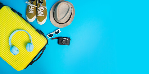 Top view suitcase with sun glasses, hat and camera on blue  background. travel concept.