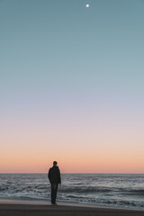Fototapeta premium person walking on the beach at sunset