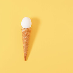 Creative Easter concept with egg and cornet on pastel yellow background.