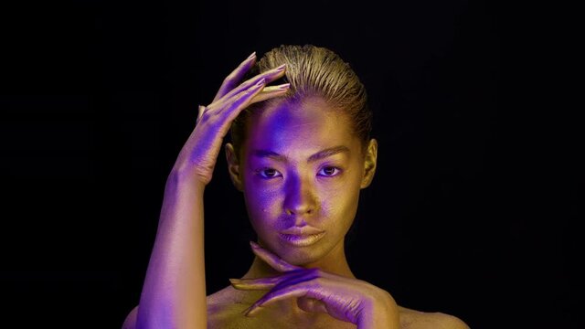 Beautiful Woman With Golden Skin Touching Face On Black Background