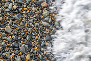 Beautiful texture of colorful smooth stones is on the beach by sea