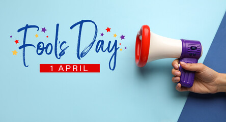 Female hand with funny megaphone on color background. April Fool's Day celebration
