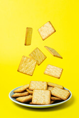 Crackers on a yellow background. Crackers fall into the plate. fresh biscuits