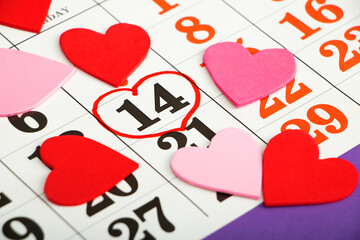 Close up calendar with date stamped Valentines Day February 14 and pink and red decorative hearts