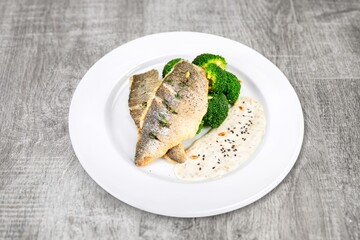 Plate of fried fish fillet with vegetables on the desk