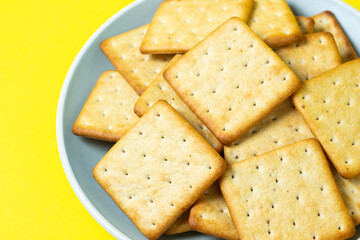 Crackers on a yellow background. Fresh crispy crackers on a plate.