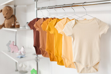 Baby bodysuits hanging near light wall in room