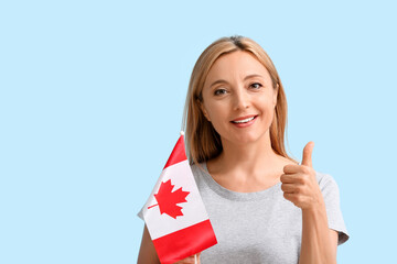 Mature woman with Canadian flag showing thumb-up on color background