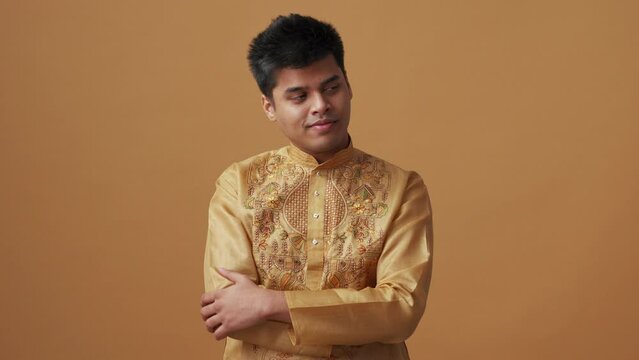 Happy Indian man in national cloth looking at the camera in the orange studio