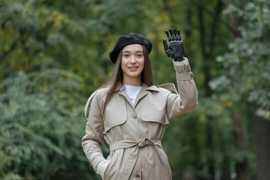 a happy European cyber woman with a bionic prosthesis on her arm waves to her friends. disability or amputation of limbs, bionic prosthetics of the forearm, hand and fingers. prosthetics technologies