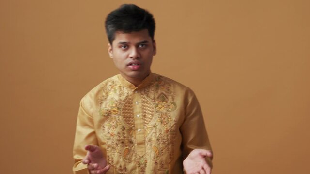 Confident Indian man in national cloth talking with camera in the orange studio