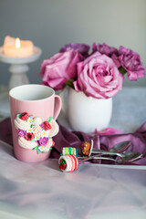 mug and spoon decorated with polymer clay against a background of a bouquet of roses, handmade