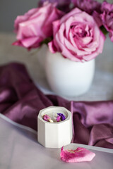 Obraz na płótnie Canvas a candle in a white pot on a purple fabric, handmade