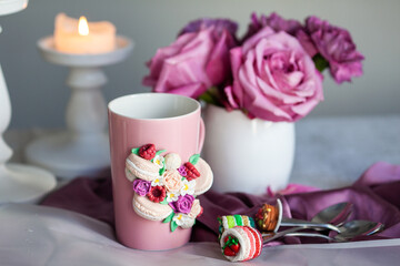 mug and spoon decorated with polymer clay against a background of a bouquet of roses, handmade