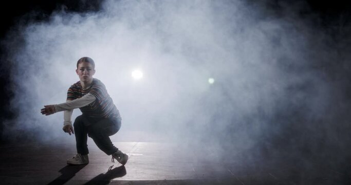 silhouette of a female dancer performing hip hop dance in slow motion with light and smoke background