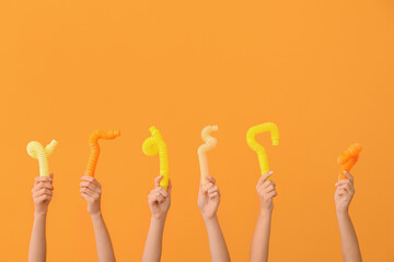 Hands with popular pop tubes on color background