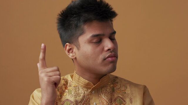 Meditative Indian man in national cloth having idea in the orange studio