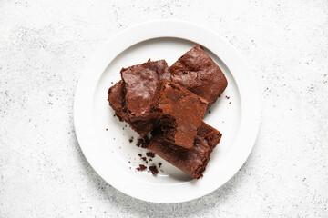 Plate with pieces of tasty chocolate brownie on white background
