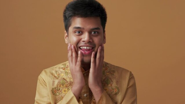 Surprised Indian man in national cloth talking something in the orange studio