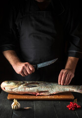 The chef prepares silver carp fish. Preparing for the preparation of fish food for the holidays. Working environment in the restaurant kitchen