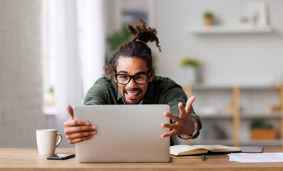 Overjoyed african american man looking at laptop screen feeling excited after receiving job offer