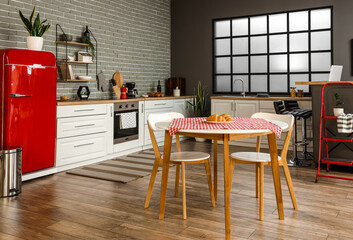 Interior of stylish kitchen with red fridge, white counters and dining table