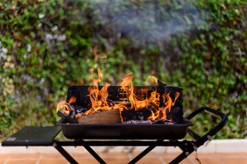 Barbecue grill with big fire flame in a garden on open air - obrazy, fototapety, plakaty