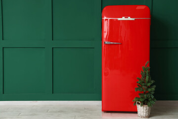Red fridge and small Christmas tree near green wall
