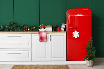 Red fridge with small Christmas tree in kitchen decorated for holiday