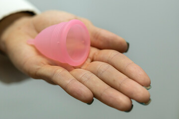 Doctor's hand holds on her palm a menstrual cup. Gynecology and health concept.