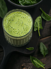 Glass of homemade healthy green smoothie with fresh baby spinach