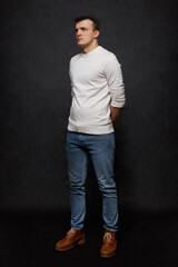 Full length portrait of a young man in the studio on a black background. Half a turn.