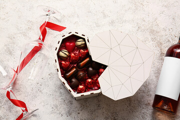 Heart shaped box with tasty chocolate candies and glasses on light background