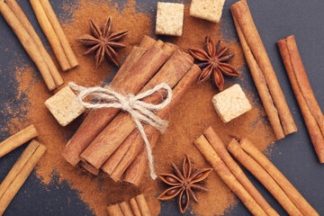 Cinnamon sticks with powder and sugar cubes on black background