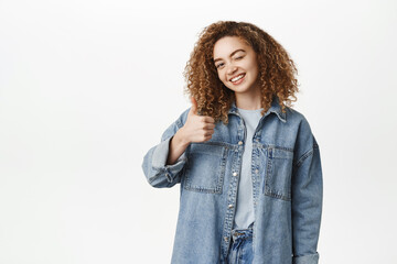 Happy beautiful girl showing thumbs up, like and approve, recommending smth good, praising or complimenting, standing over white background