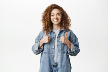 Happy beautiful girl showing thumbs up, like and approve, recommending smth good, praising or...