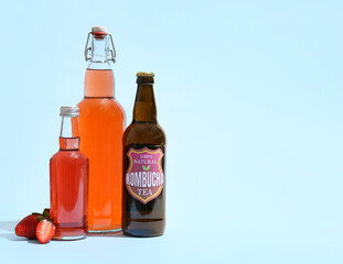 Bottles of tasty strawberry kombucha on blue background