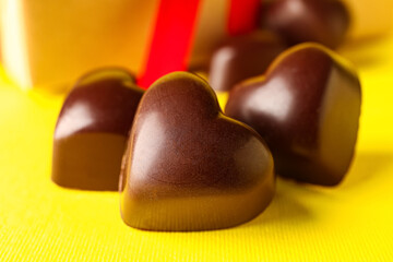 Tasty heart-shaped candies on yellow background, closeup