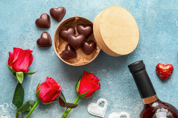 Composition with tasty heart-shaped candies, flowers and bottle of wine on color background