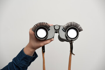 human hands holding binoculars with funny, false eyelashes