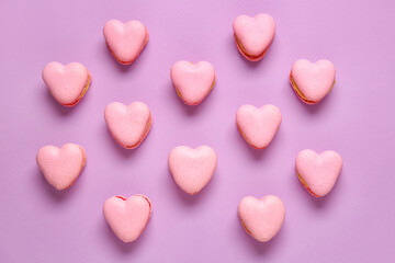 Tasty heart-shaped macaroons on purple background
