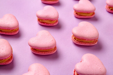 Fototapeta na wymiar Tasty heart-shaped macaroons on purple background, closeup