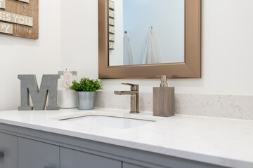 Detail of modern bathroom sink with white countertop and light blue gray cabinetry.