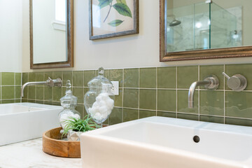Detail of modern bathroom sink with chrome faucet and green tile backsplash.