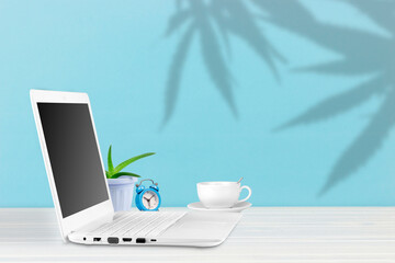 work place. Laptop with blank screen on office desk in cozy environment, with coffee and home plant